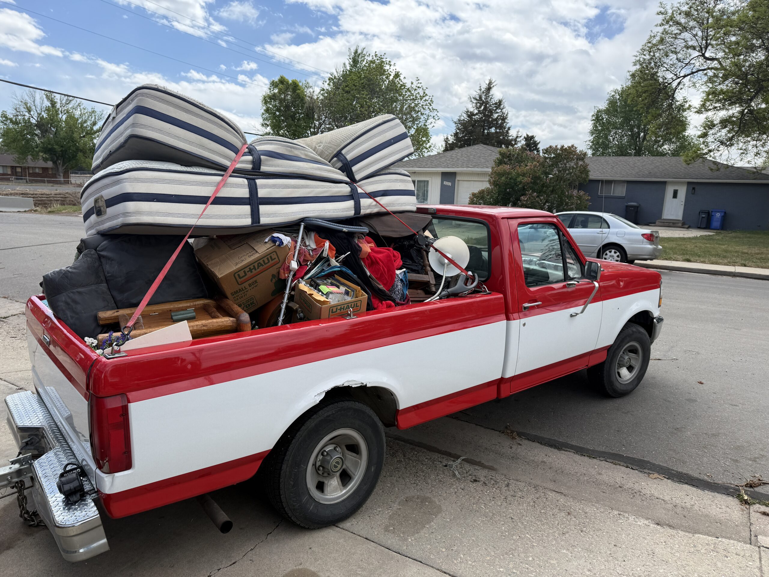 Red Truck Delivery red pickup loaded with mattresses, boxes, and junk — same-day junk removal across Northern Colorado